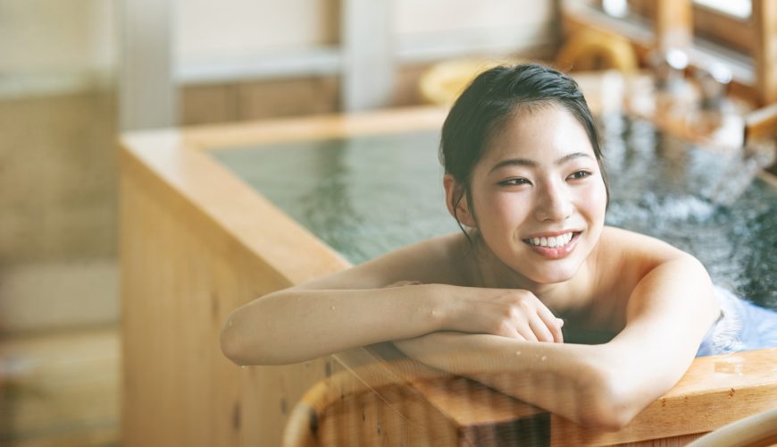 Một cô gái thư giãn ngâm mình trong bồn tắm gỗ Onsen.