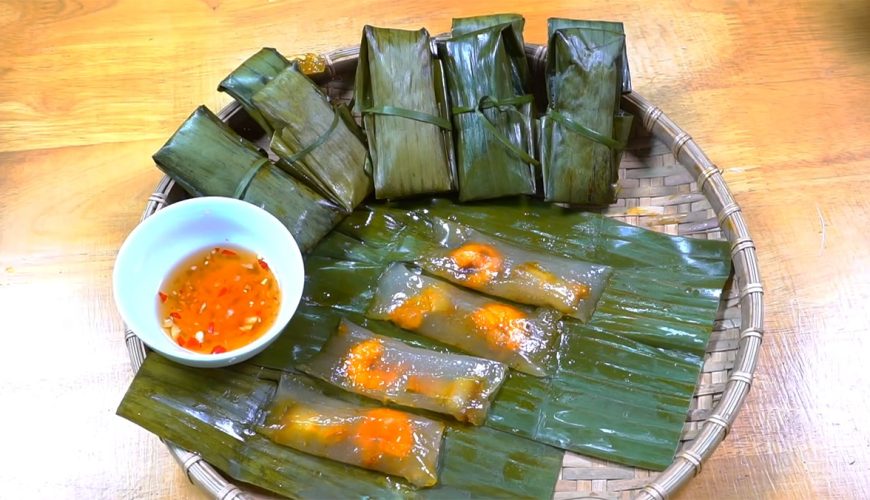 Bánh lọc trong suốt, nhân tôm đỏ tươi, được gói trong lá chuối và dùng kèm nước chấm.